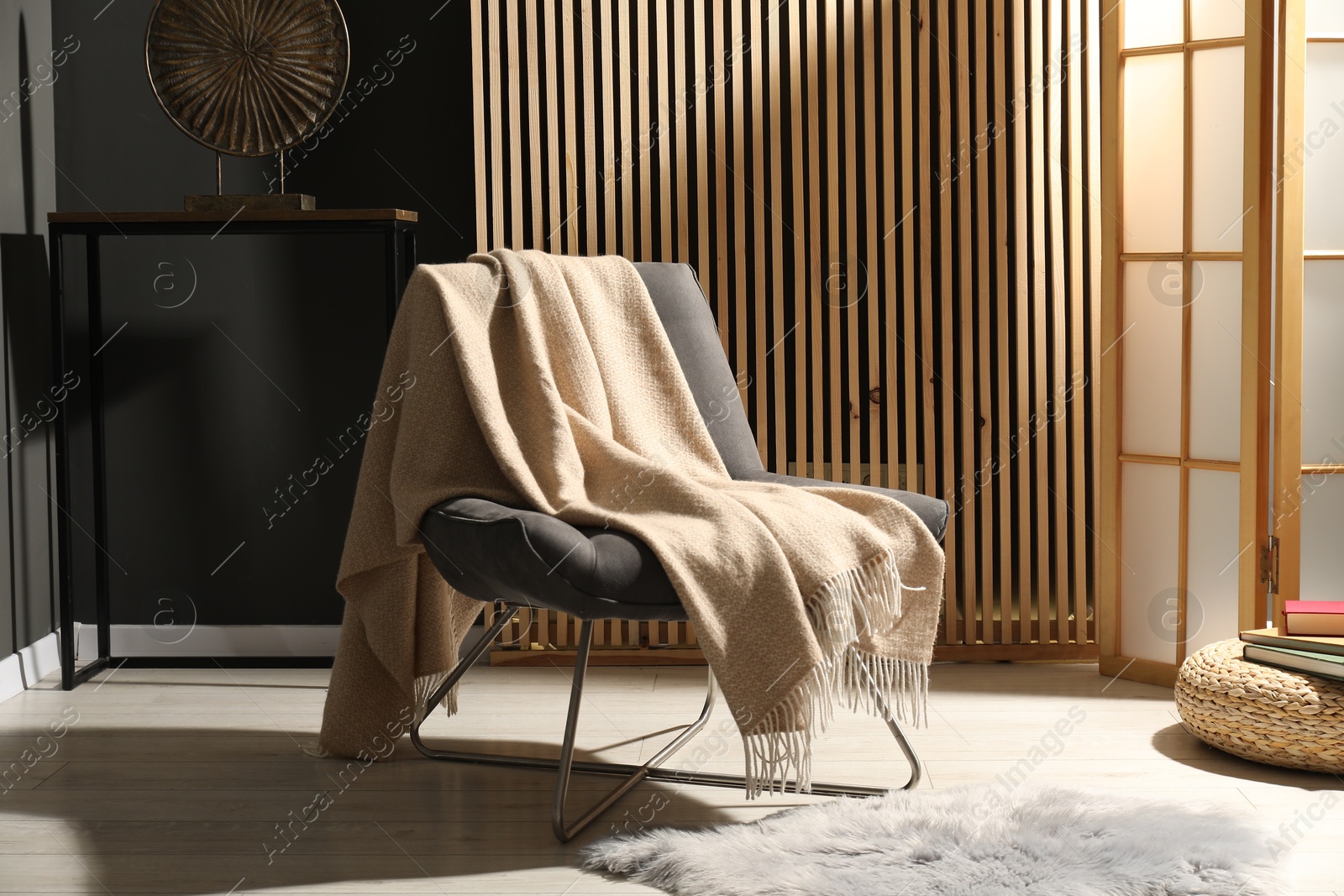 Comfortable armchair with woolen blanket in room Photo of Comfortable armchair with woolen blanket in room