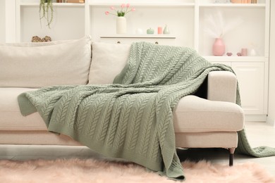 Photo of Green woolen blanket on sofa in room