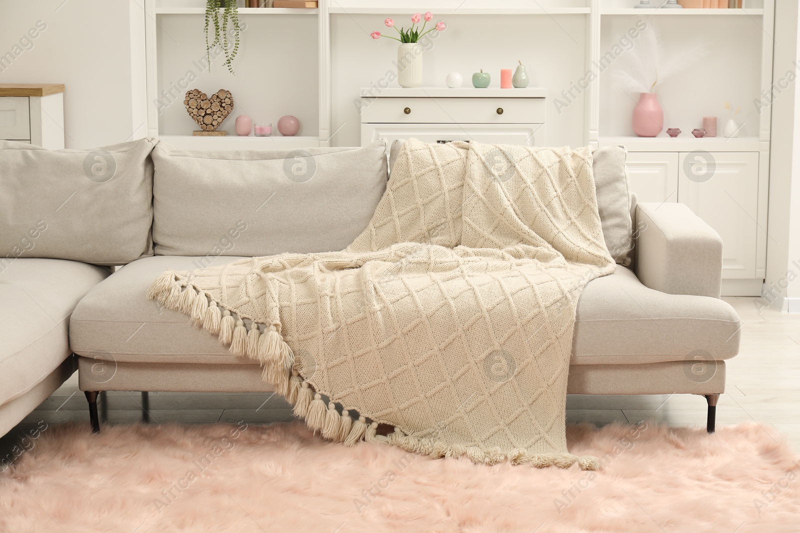 Beige woolen blanket on sofa in room Photo of Beige woolen blanket on sofa in room