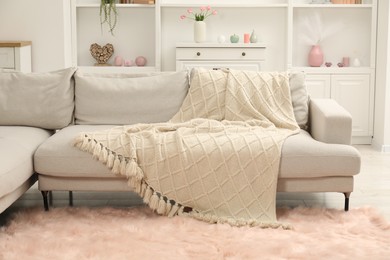 Photo of Beige woolen blanket on sofa in room