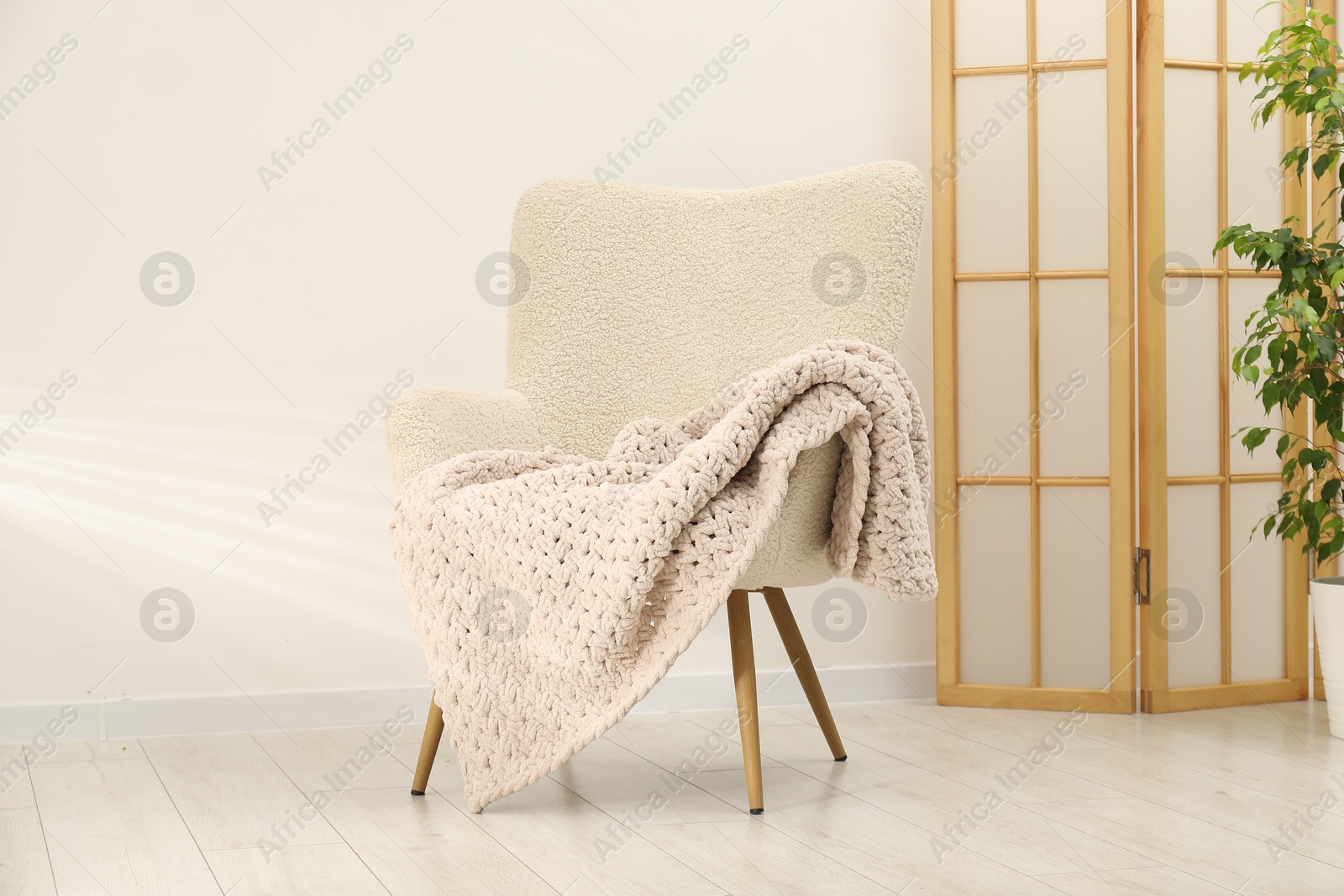Comfortable armchair with woolen blanket in room Photo of Comfortable armchair with woolen blanket in room