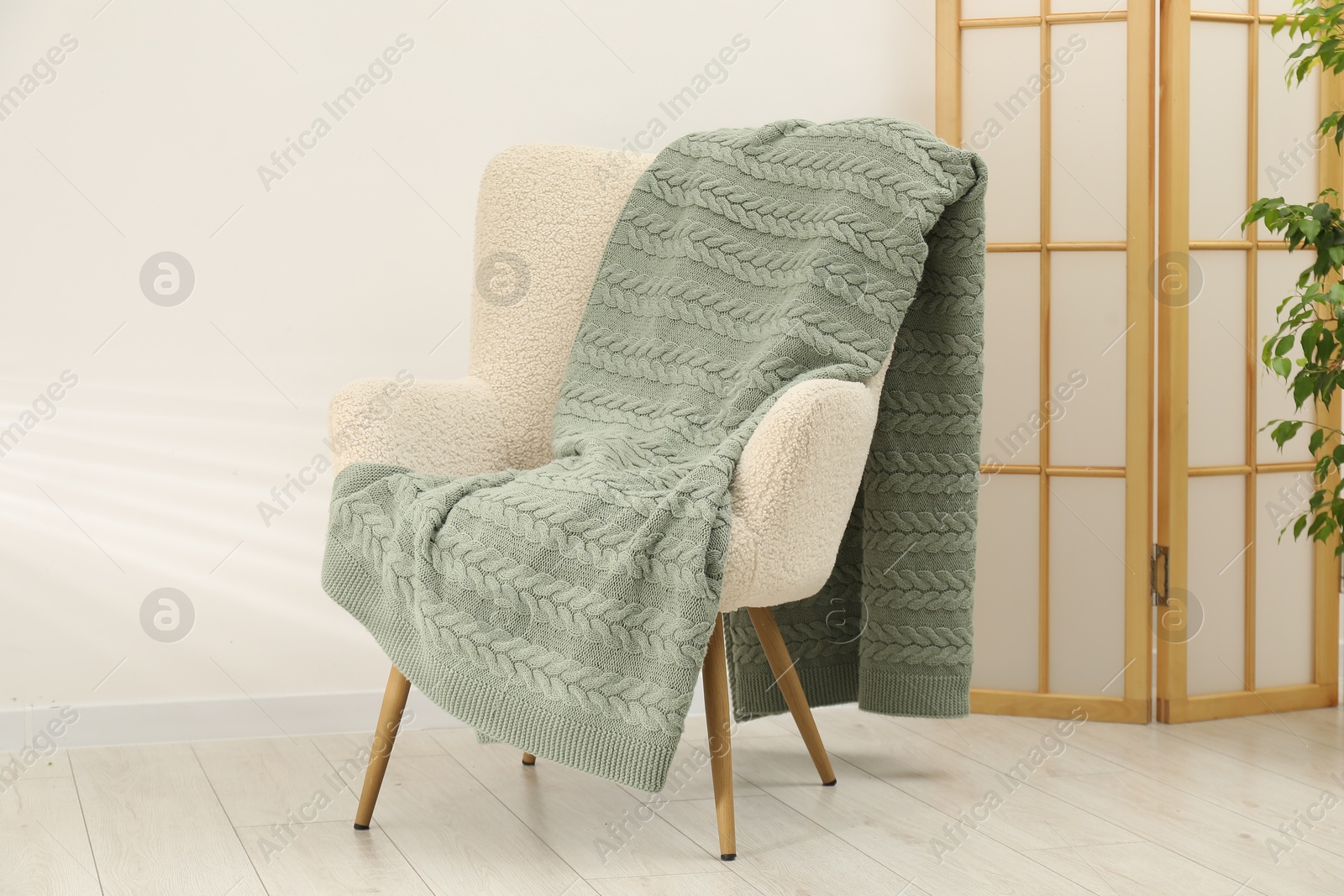Comfortable armchair with green woolen blanket indoors Photo of Comfortable armchair with green woolen blanket indoors
