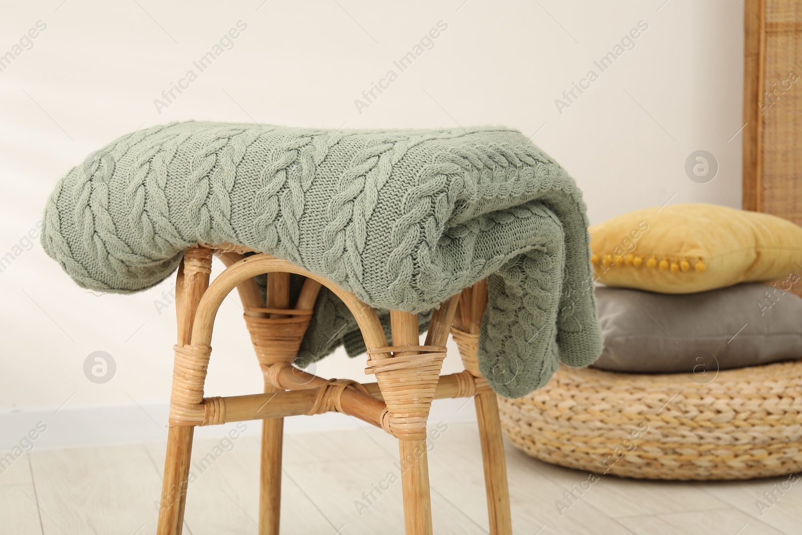 Green woolen blanket on stool indoors, closeup Photo of Green woolen blanket on stool indoors, closeup