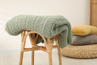 Photo of Green woolen blanket on stool indoors, closeup