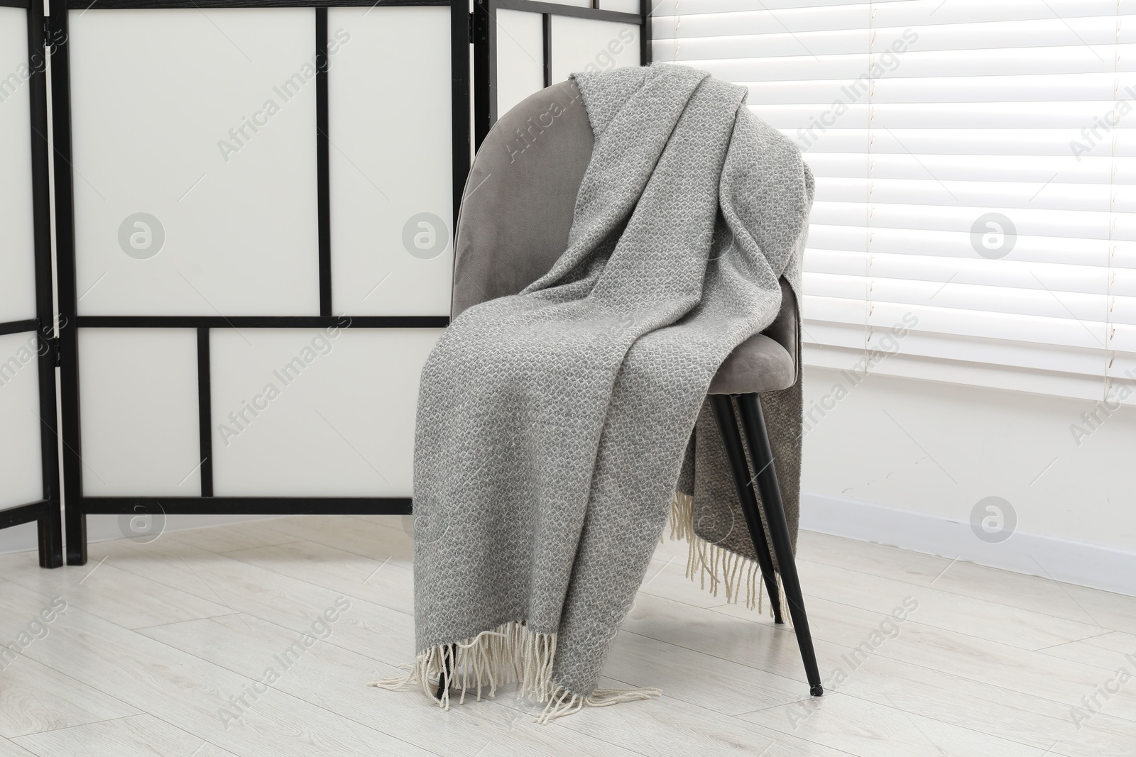 Photo of Comfortable armchair with gray woolen blanket indoors