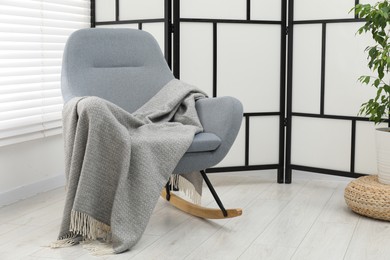 Photo of Comfortable armchair with gray woolen blanket indoors