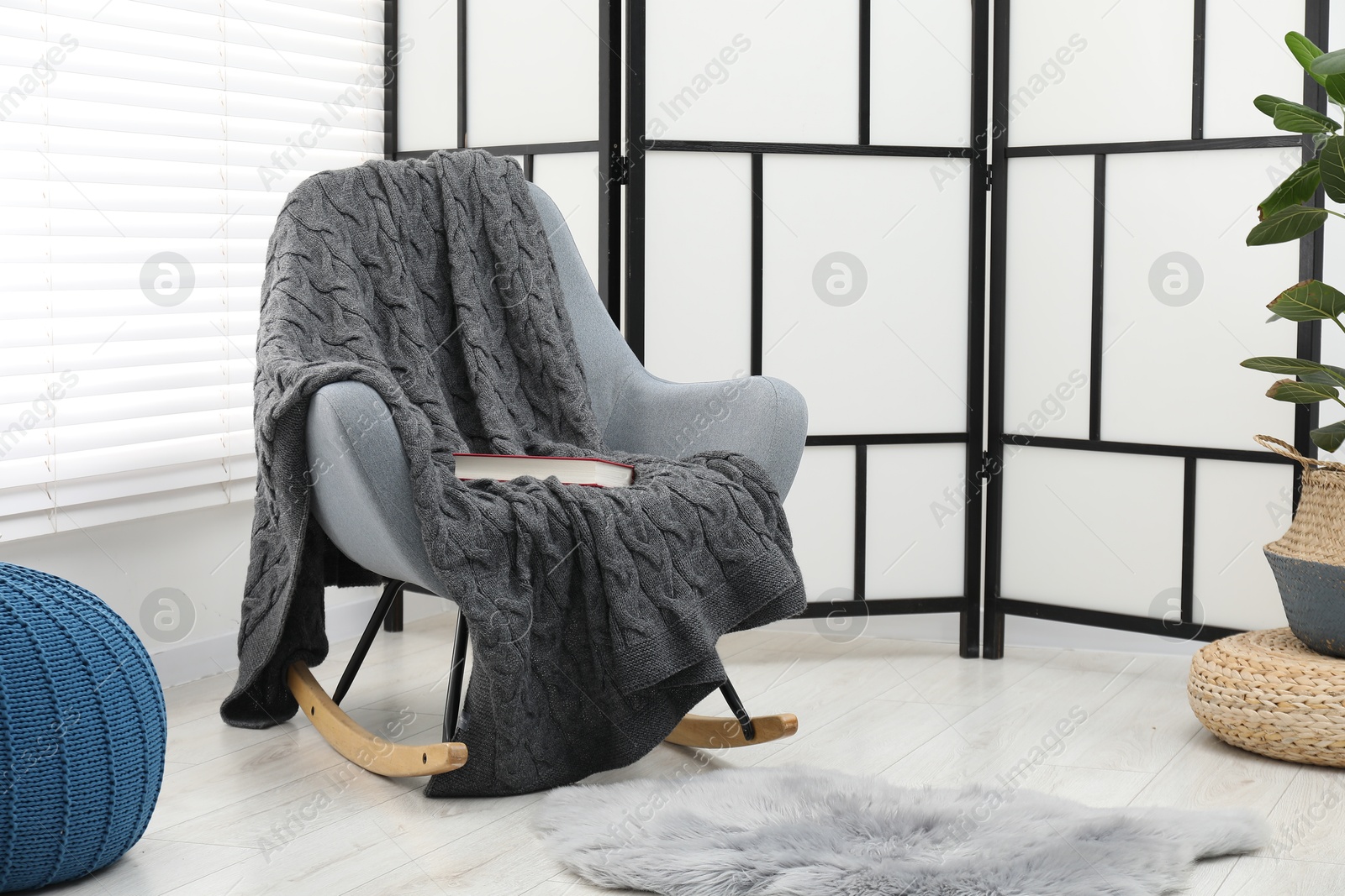 Comfortable armchair with gray woolen blanket and book indoors Photo of Comfortable armchair with gray woolen blanket and book indoors