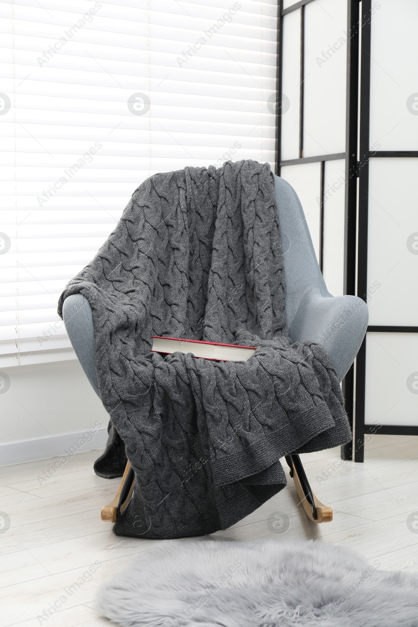 Comfortable armchair with gray woolen blanket and book indoors Photo of Comfortable armchair with gray woolen blanket and book indoors