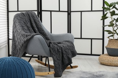 Photo of Comfortable armchair with gray woolen blanket indoors