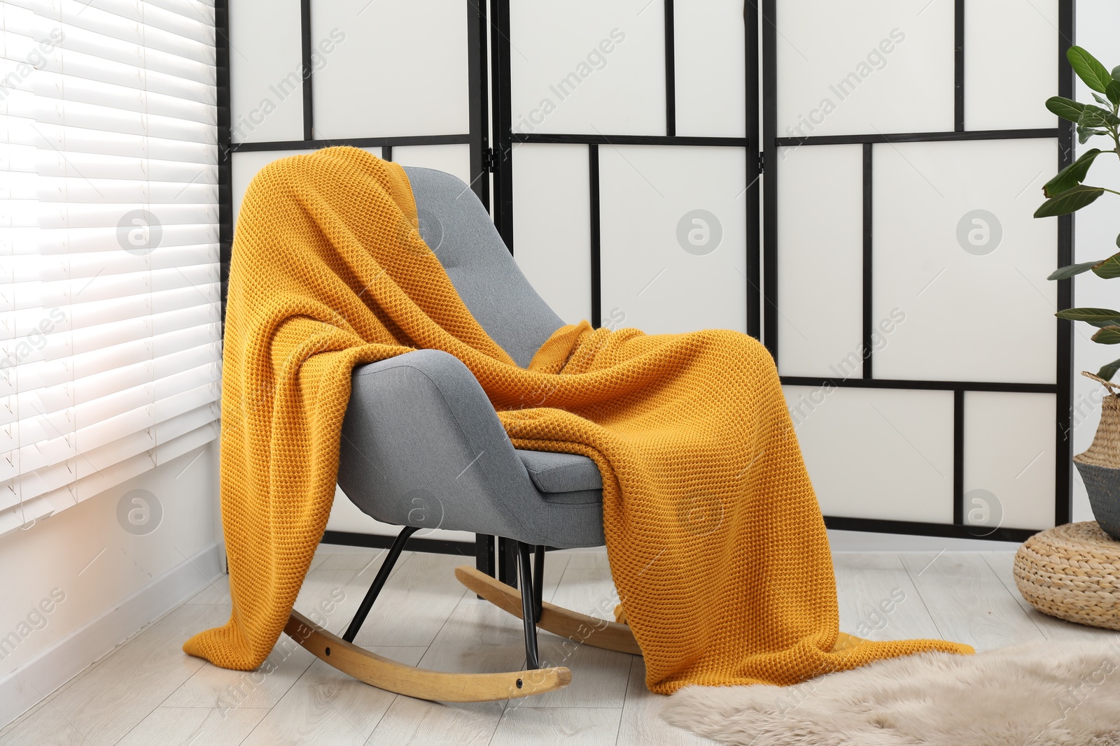 Comfortable armchair with orange woolen blanket indoors Photo of Comfortable armchair with orange woolen blanket indoors