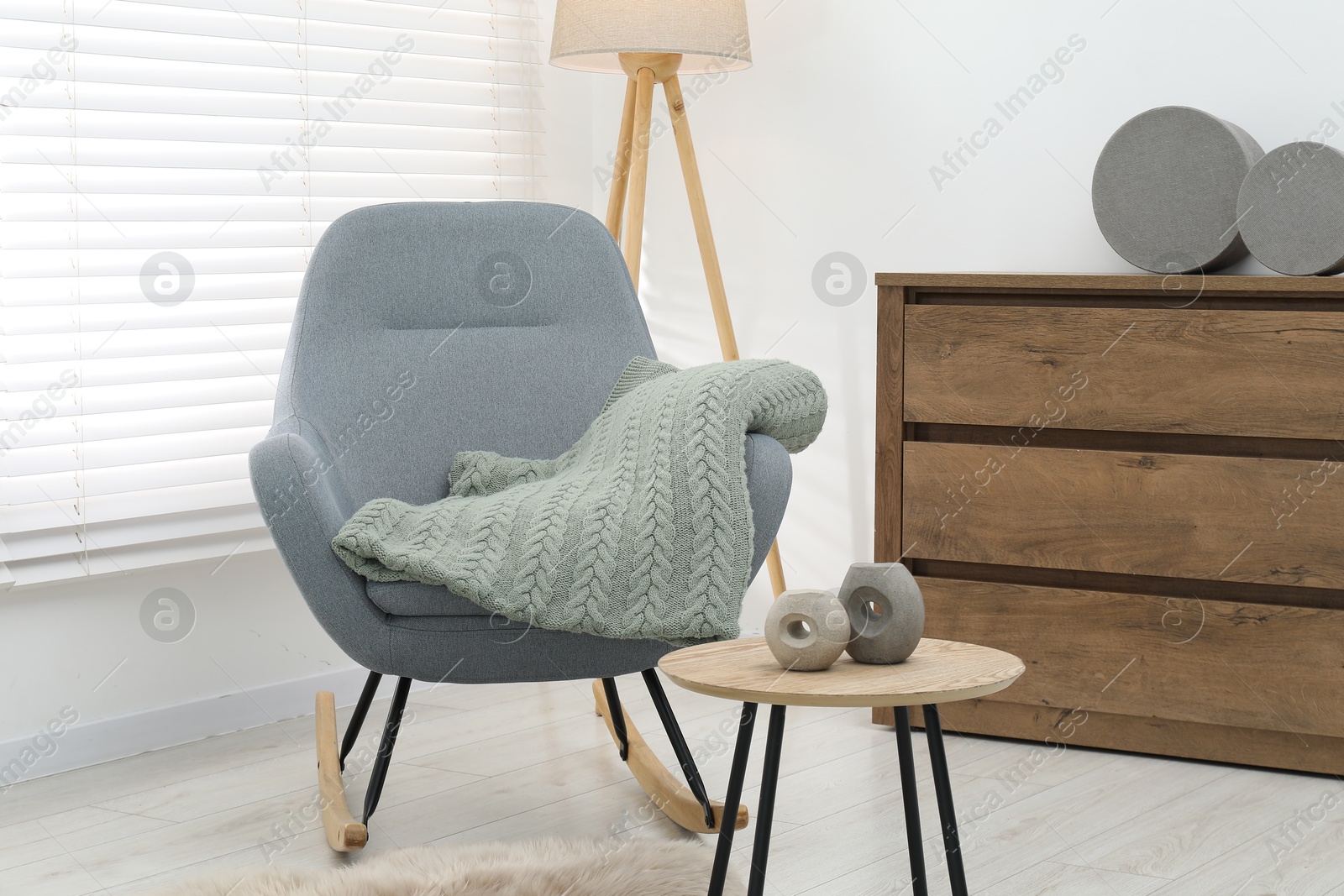 Comfortable armchair with green woolen blanket and decor on wooden table indoors Photo of Comfortable armchair with green woolen blanket and decor on wooden table indoors