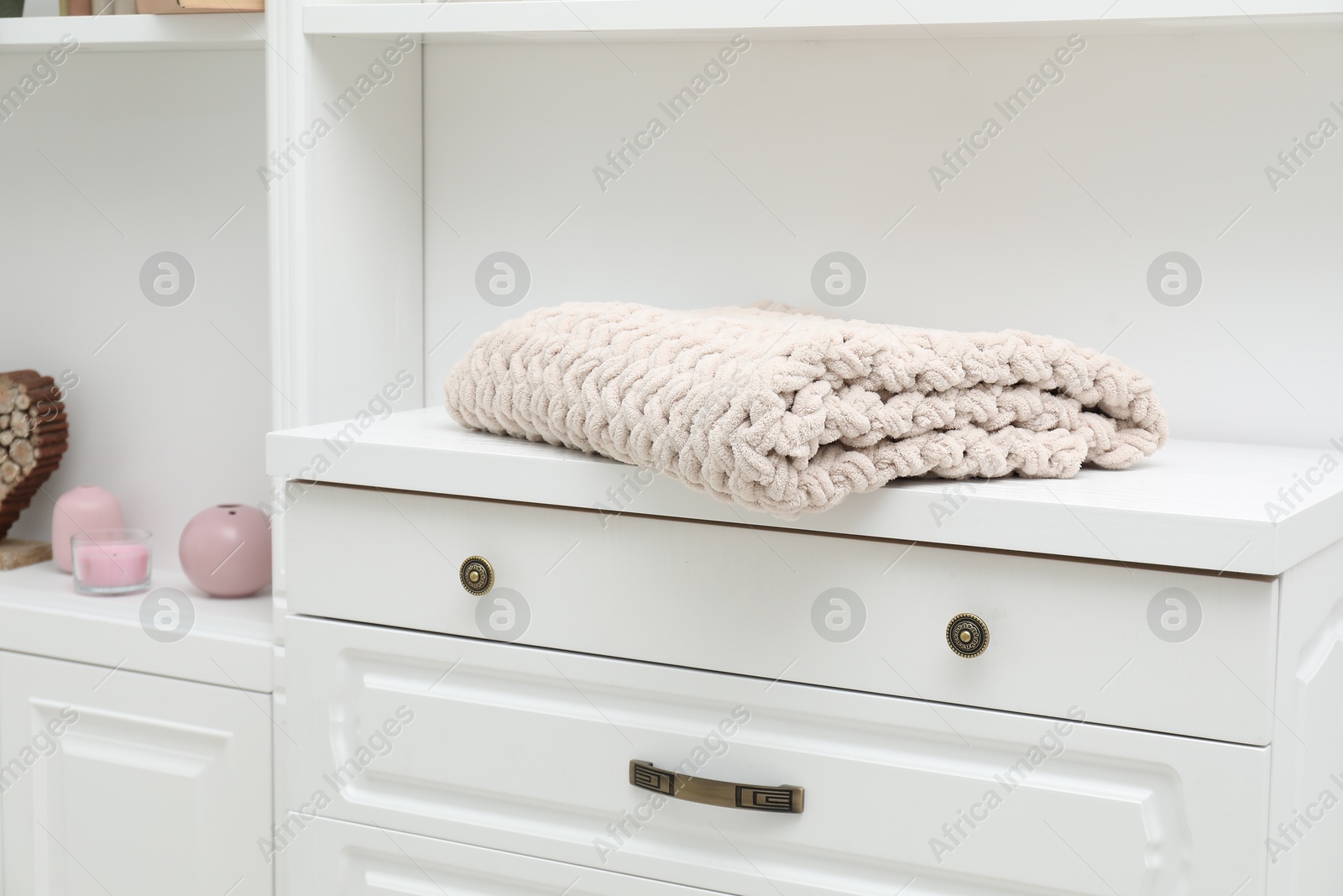 Woolen blanket on white chest of drawers indoors, closeup Photo of Woolen blanket on white chest of drawers indoors, closeup
