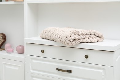 Photo of Woolen blanket on white chest of drawers indoors, closeup