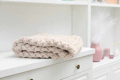 Photo of Woolen blanket on white chest of drawers indoors, closeup