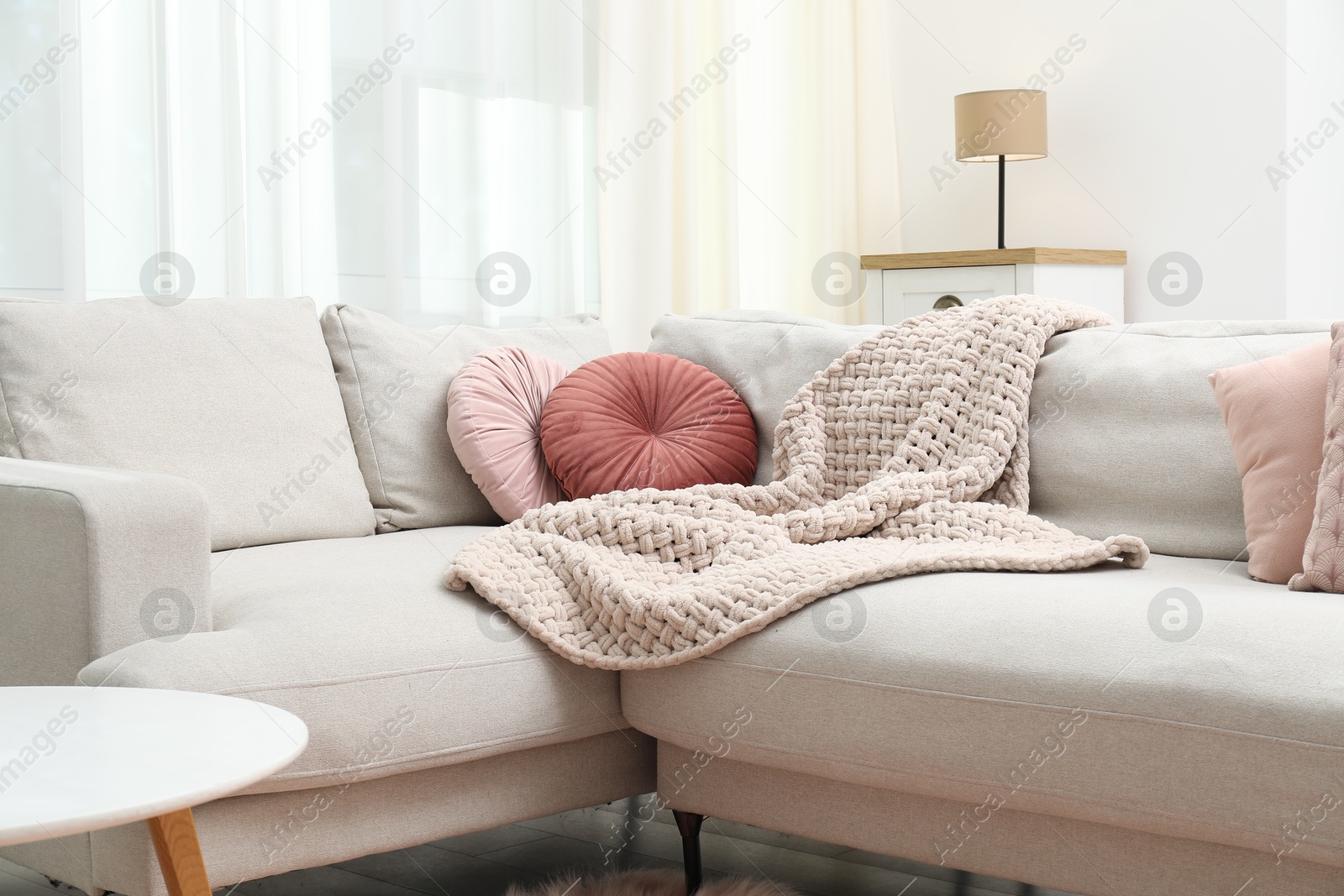 Woolen blanket and pillows on sofa indoors Photo of Woolen blanket and pillows on sofa indoors