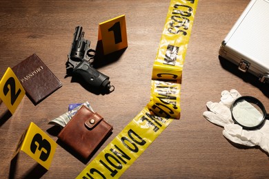 Photo of Forensic expertise. Crime scene with evidence, markers and police tape on wooden background