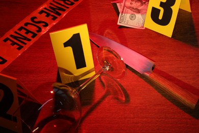 Photo of Forensic expertise. Crime scene with evidence, markers and police tape on wooden background, closeup. Color toned effect