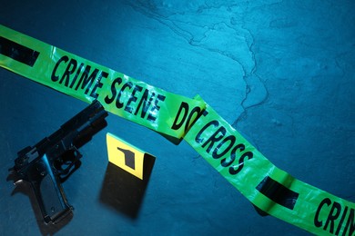 Photo of Forensic expertise. Crime scene tape and gun on color background, flat lay. Space for text