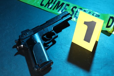 Photo of Forensic expertise. Crime scene tape and gun on color background, closeup