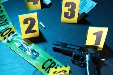 Photo of Forensic expertise. Crime scene with evidence, markers and police tape on blue background, closeup. Color toned effect