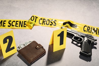 Photo of Forensic expertise. Crime scene with evidence, markers and police tape on light grey background, closeup