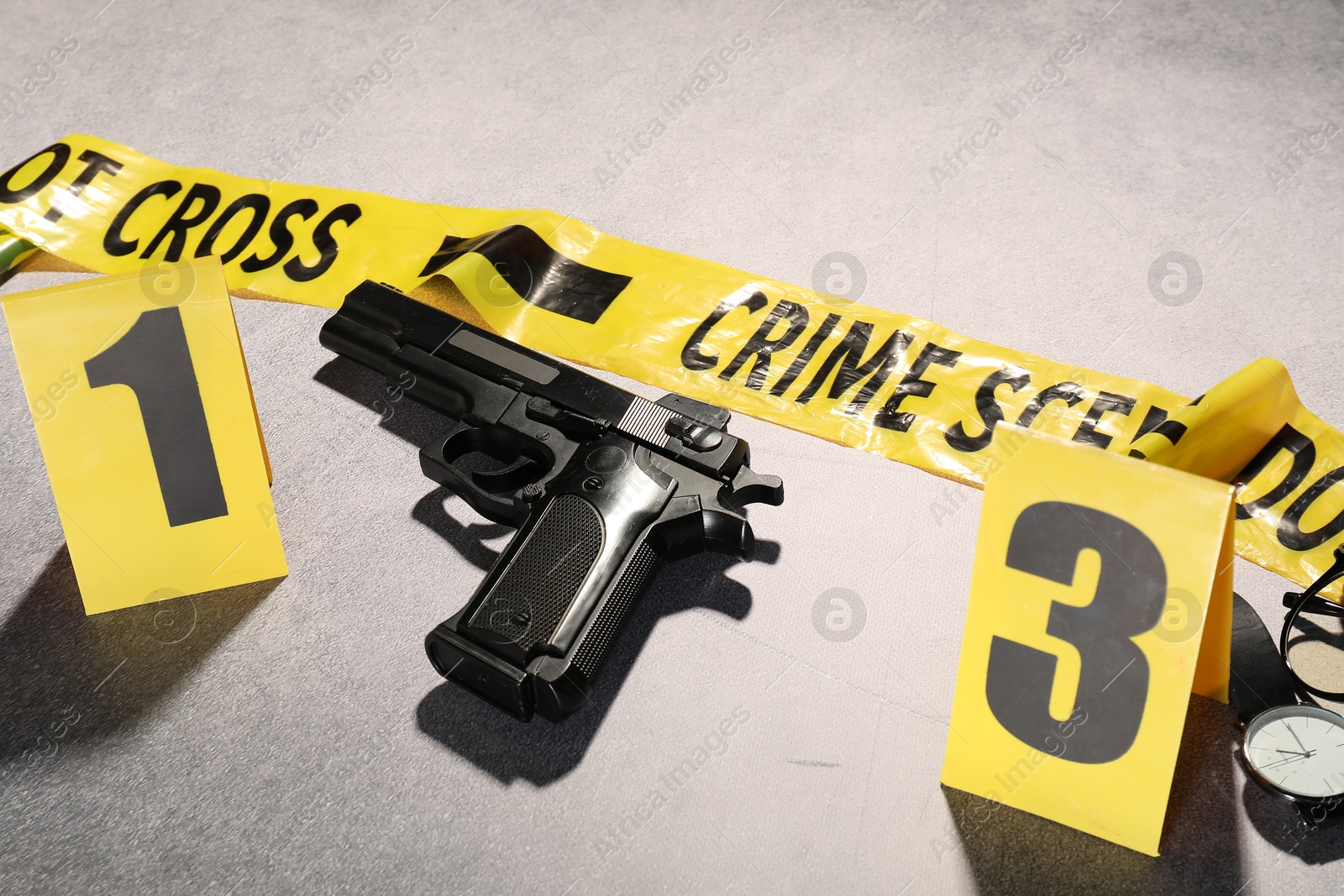 Forensic expertise. Crime scene with evidence, markers and police tape on light grey background, closeup Photo of Forensic expertise. Crime scene with evidence, markers and police tape on light grey background, closeup