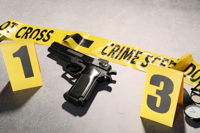 Photo of Forensic expertise. Crime scene with evidence, markers and police tape on light grey background, closeup