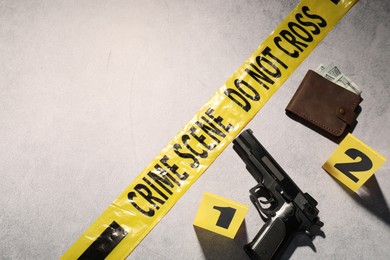 Photo of Forensic expertise. Crime scene with evidence, markers and police tape on light grey background, space for text