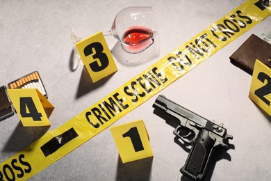 Photo of Forensic expertise. Crime scene with evidence, markers and police tape on light grey background