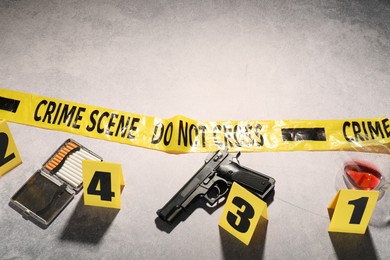 Photo of Forensic expertise. Crime scene with evidence, markers and police tape on light grey background, space for text