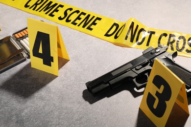 Photo of Forensic expertise. Crime scene with evidence, markers and police tape on light grey background, closeup