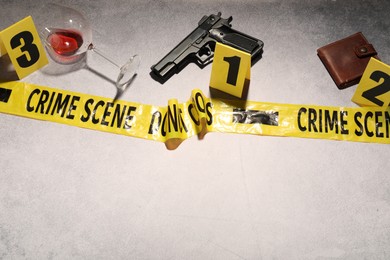 Photo of Forensic expertise. Crime scene with evidence, markers and police tape on light grey background, space for text