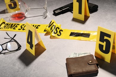 Photo of Forensic expertise. Crime scene with evidence, markers and police tape on light grey background, closeup