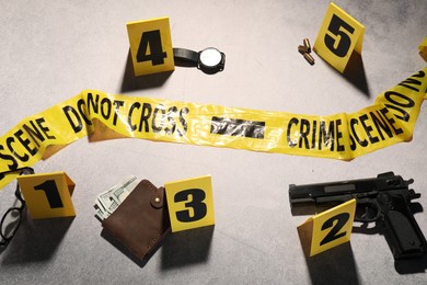 Photo of Forensic expertise. Crime scene with evidence, markers and police tape on light grey background