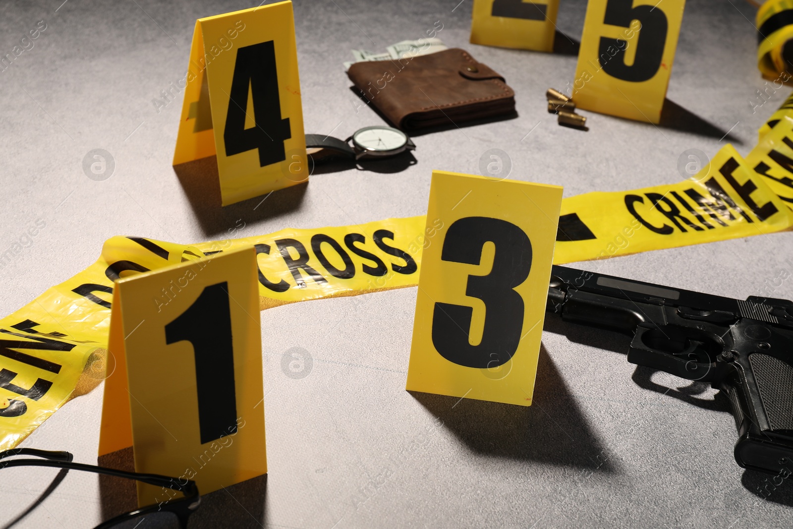 Forensic expertise. Crime scene with evidence, markers and police tape on light grey background, closeup Photo of Forensic expertise. Crime scene with evidence, markers and police tape on light grey background, closeup