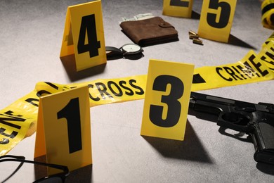 Photo of Forensic expertise. Crime scene with evidence, markers and police tape on light grey background, closeup