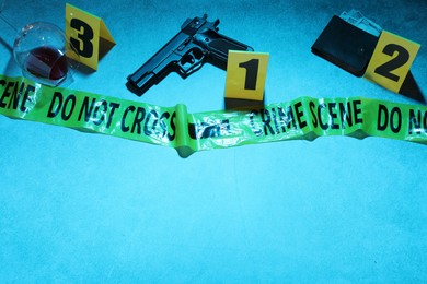 Photo of Forensic expertise. Crime scene with evidence, markers and police tape on blue background, space for text. Color toned effect