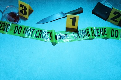 Photo of Forensic expertise. Crime scene with evidence, markers and police tape on blue background, space for text. Color toned effect