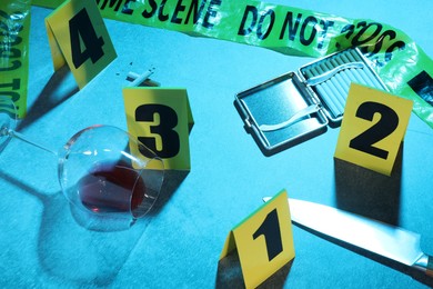 Photo of Forensic expertise. Crime scene with evidence, markers and police tape on blue background. Color toned effect