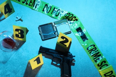 Photo of Forensic expertise. Crime scene with evidence, markers and police tape on blue background. Color toned effect