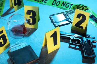 Photo of Forensic expertise. Crime scene with evidence, markers and police tape on blue background, closeup. Color toned effect