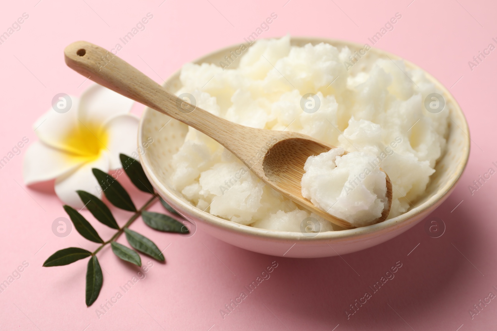 Photo of Natural shea butter, plumeria flower and leaves on pink background, closeup