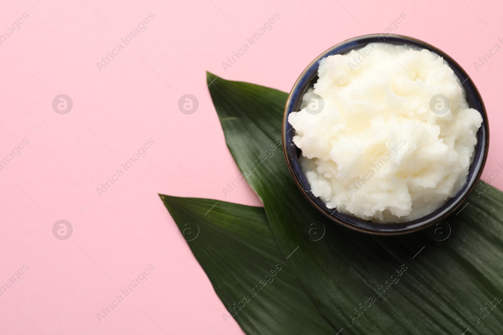 Natural shea butter and leaves on pink background, top view. Space for text Photo of Natural shea butter and leaves on pink background, top view. Space for text