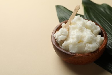 Photo of Natural shea butter and leaves on beige background, closeup. Space for text
