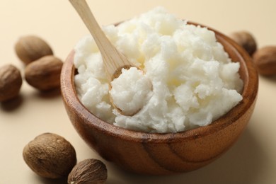 Photo of Natural shea butter and nuts on beige background, closeup