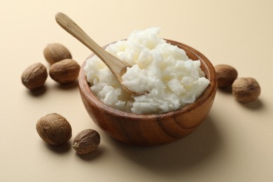 Photo of Natural shea butter and nuts on beige background, closeup