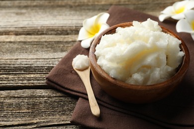 Photo of Natural shea butter and plumeria flowers on wooden table, closeup. Space for text