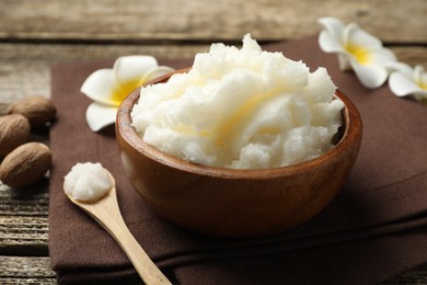 Photo of Natural shea butter and plumeria flowers on wooden table, closeup