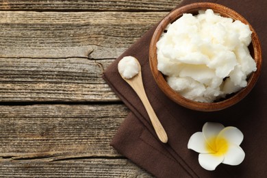 Photo of Natural shea butter and plumeria flower on wooden table, flat lay. Space for text