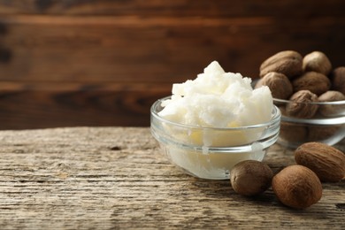 Photo of Natural shea butter and nuts on wooden table, closeup. Space for text